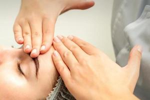 jovem mulher recebendo facial massagem foto