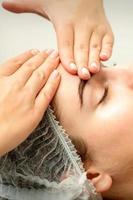 jovem mulher recebendo facial massagem foto