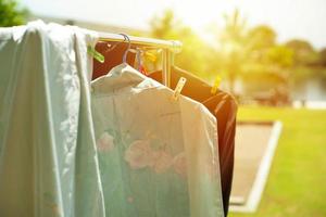 closeup muitos pedaços de trapos pendurados em um prendedor de roupa para secar à luz do sol com uma paisagem borrada de fundo foto