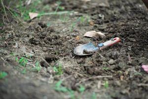 closeup de colher de plantio suja no solo com primeiro plano desfocado de grama foto