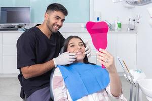 dentista e paciente admirando dentes foto