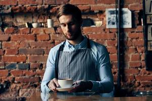 masculino garçom avental serviço café copo tijolo parede foto