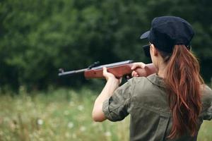 militares mulher segurando uma arma de fogo Caçando alvo traseiro Visão verde macacão foto