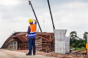 traseiro Visão do engenheiro debaixo inspeção e verificação projeto às a construção site, capataz trabalhador dentro capacete de segurança às a a infraestrutura construção local foto