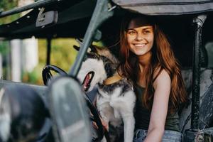 mulher e rouco cachorro alegremente viajando dentro carro sorrir com dentes outono andar com bicho de estimação, viagem com cachorro amigo abraços e danças foto