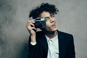 fotógrafo com uma Câmera dentro uma clássico terno encaracolado cabelo estúdio modelo foto