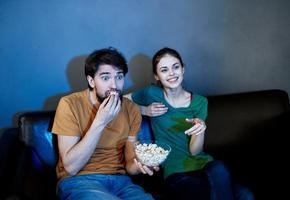 uma casado casal em a sofá assistindo televisão e Pipoca dentro de casa foto