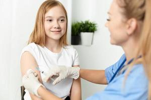 mulher médico dando uma menina a injeção dentro a braço saúde remédio cobiçado vacinação foto