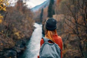 mulher com mochila dentro natureza em a ponte perto a rio montanhas aventura foto