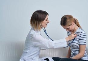 mulher médico com estetoscópio e paciente às a recepção foto