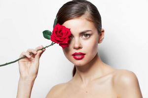 mulher retrato vermelho lábios nu ombros do uma rosa flor perto a face Claro pele foto