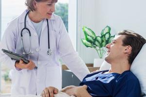 a médico é examinando a paciente dentro a hospital. caucasiano fêmea médico falando para masculino paciente deitado dentro hospital cama. foto