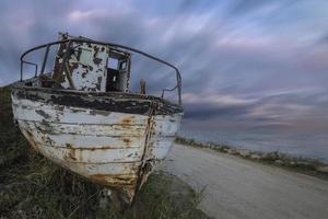 a abandonado velho de madeira pescaria barco em a de praia com surpreendente céu foto