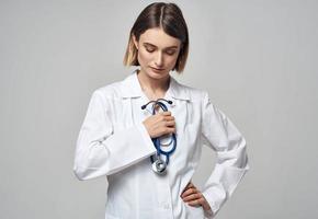 uma profissional médico dentro uma médico vestido detém uma estetoscópio foto