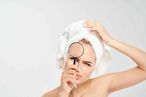 mulher com nu ombros segurando uma ampliação vidro perto face dermatologia Claro pele foto