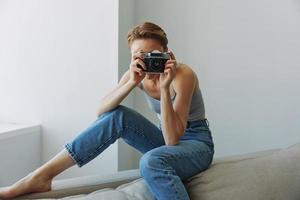 mulher fotógrafo tiroteio dentro estúdio em velho filme Câmera às casa em sofá retrato, branco fundo, livre cópia de espaço, freelance fotógrafo foto