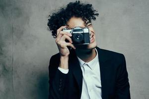 fotógrafo com uma Câmera dentro uma clássico terno encaracolado cabelo estúdio modelo foto