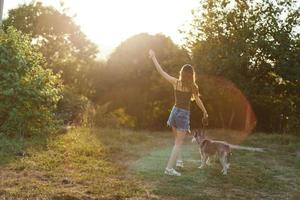 uma mulher corre dela costas para a Câmera com uma cachorro dentro a floresta durante a tarde andar dentro a floresta às pôr do sol dentro outono. estilo de vida Esportes Treinamento com seu Amado cachorro foto