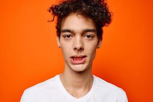 alegre cara dentro uma branco camiseta emoção fechar-se laranja fundo foto