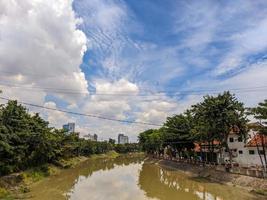 uma Visão do Castanho rio com azul céu e árvores ao lado isto dentro Surabaia, Indonésia foto