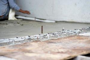 foco seletivo no aço de reforço no piso de cimento no canteiro de obras com trabalhador desfocado no fundo foto
