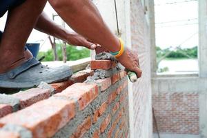 closeup mãos de trabalhador instalando os pedreiros para construir a parede no canteiro de obras. foto