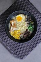 japonês ramen com ovo, arroz e legumes dentro uma Preto tigela foto