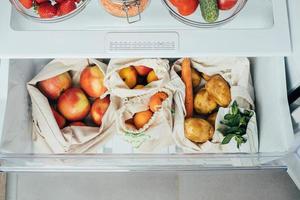 zero desperdício conceito. fresco legumes e frutas dentro eco algodão bolsas dentro uma geladeira a partir de mercado. foto