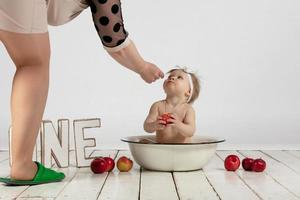 mãe e uma um ano de idade bebê. uma lindo pequeno menina é ser preparado para uma foto atirar. da mãe mãos e pequeno filha.