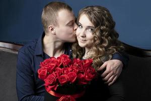 a cara e a menina com uma ramalhete do rosas. uma jovem casal. amantes. uma homem Beijos uma lindo mulher. foto