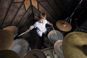 a Garoto aprende para jogar a bateria. a criança atrás a tambor kit. foto