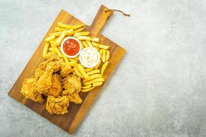asas de frango frito com batata frita e tomate ou ketchup e molho de maionese foto