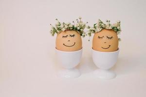 dois ovos com flores em seus cabeças estão decorado com flores e a palavras 'feliz páscoa' foto