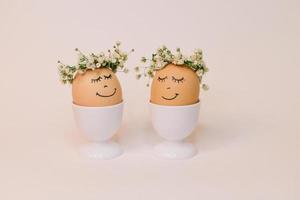 dois ovos com flores em seus cabeças estão decorado com flores e a palavras 'feliz páscoa' foto