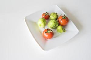 vermelho maduro suculento tomate e verde Bruxelas brotos em uma branco prato dentro fechar-se foto
