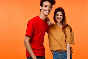 jovem casal dentro multicolorido Camisetas alegria cortada Visão laranja fundo foto