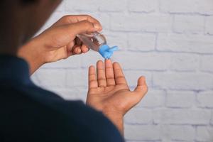 mão usando gel desinfetante para prevenir vírus foto