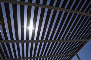 luz solar brilha através a cobertura do uma de madeira pérgola em uma ensolarado dia. foto