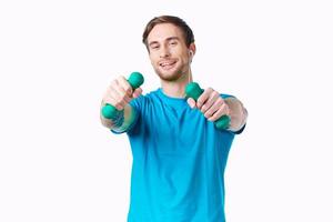 homem dentro azul camiseta segurando halteres ginástica exercício foto