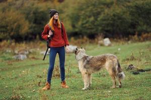 mulher caminhante com uma mochila dentro natureza com uma cachorro foto