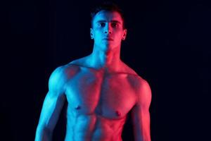 retrato do uma jovem homem com uma bombeado tronco fisiculturista fechar-se néon luz modelo foto