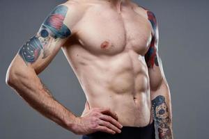 desportivo homem com uma bombeado tronco tatuagem em dele braços cortada Visão modelo foto