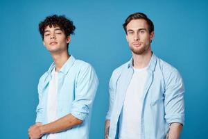 dois amigos dentro idêntico camisas e uma camiseta gesticulando com seus mãos em uma azul fundo foto