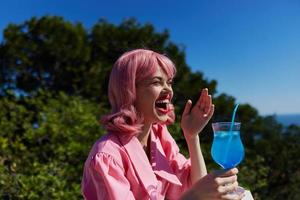 alegre mulher bebendo uma coquetel em a terraço bebendo álcool foto