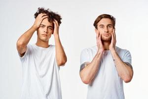 dois homens dentro branco Camisetas segurando seus cabeças emoções descontentamento foto