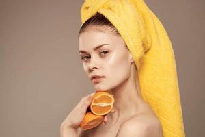 lindo mulher com amarelo toalha em dela cabeça laranjas limpar \ limpo pele cortada Visão foto