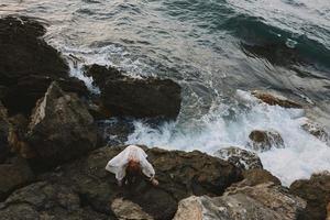 lindo mulher deitado em rochoso costa com rachaduras em rochoso superfície natureza panorama foto