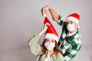 jovem casal do Natal chapéus Natal inverno Diversão médico máscaras em face foto