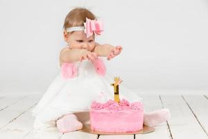 alegre criança com uma festivo bolo. engraçado menina dentro dela primeiro ano do aniversário. bebê 1 ano. foto