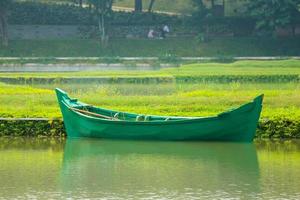 uma verde barco sem passageiros estava estacionado em a Beira do a lago. foto
